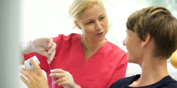 Prophylaxeassistentin erklärt den korrekten Einsatz von Zahnseide
