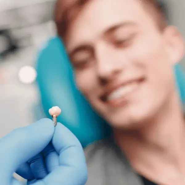 Zahnimplantat mit zufriedenem Patienten im Hintergrund