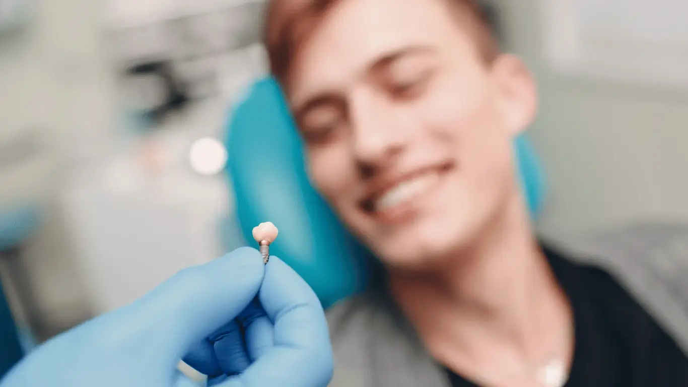 Zahnimplantat mit lächelnder Person off-focus.